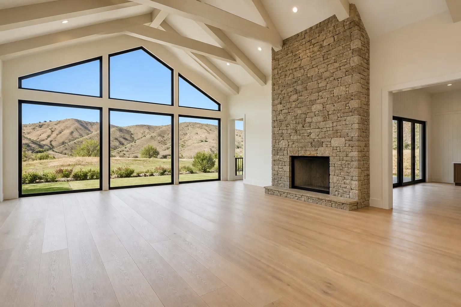 Finished great room in a new custom home with vaulted ceiling, stone fireplace, and foothills views