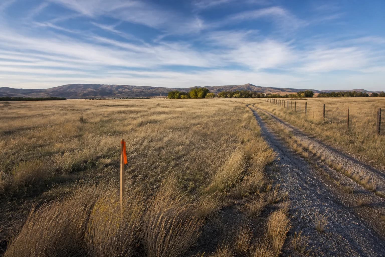 Vacant rural acreage building parcel in Canyon County, Idaho with a survey stake and desert mountains on the horizon