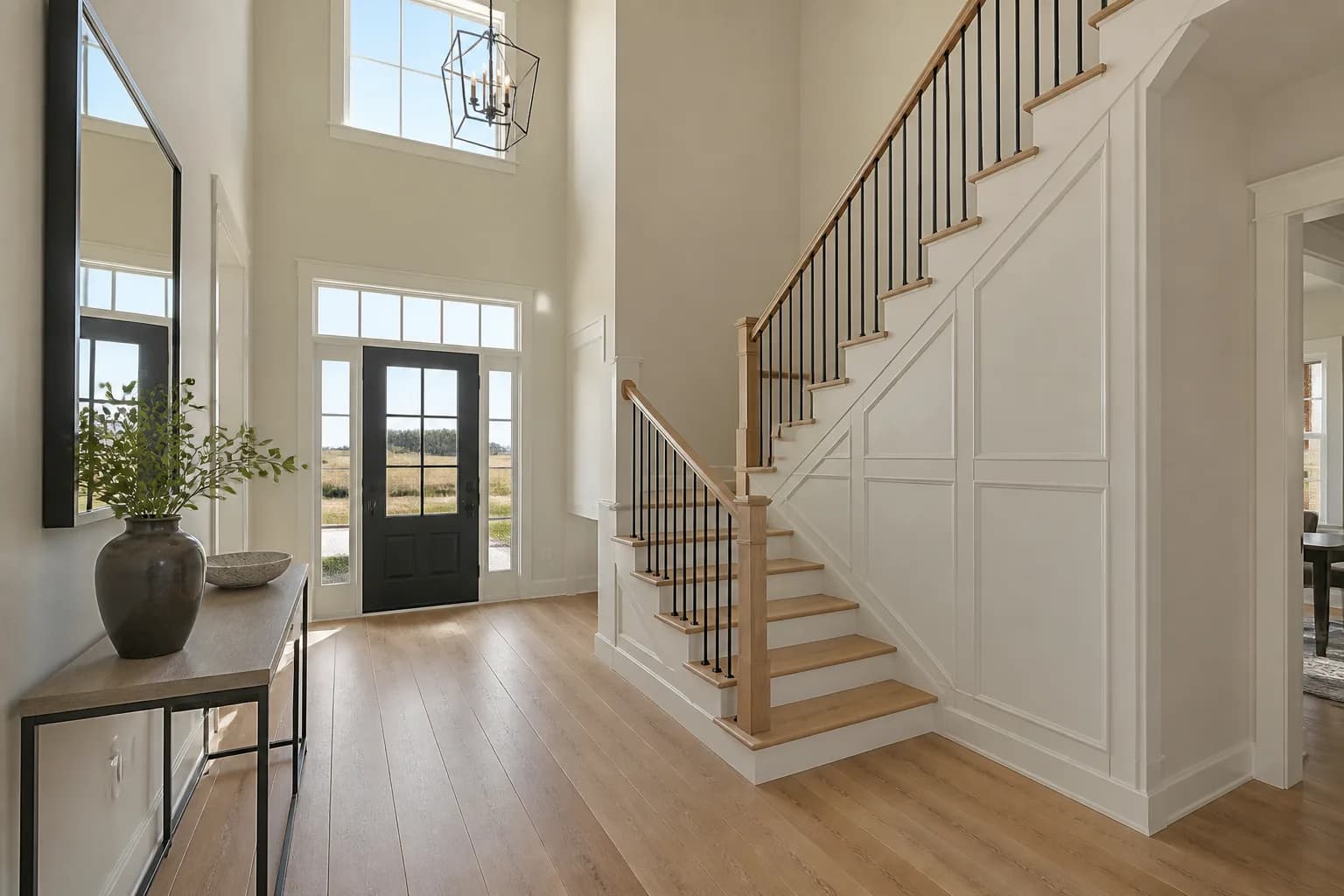 Finished entry staircase in a new Idaho home with white oak treads, black metal balusters, and a two-story foyer